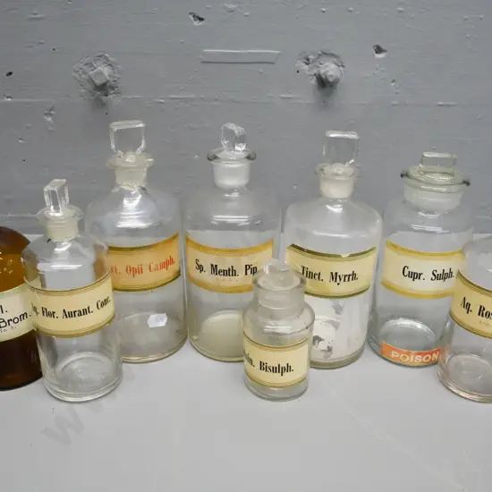 7 clear and 1 brown glass stoppered apothecary bottles with labels - tallest is H-200